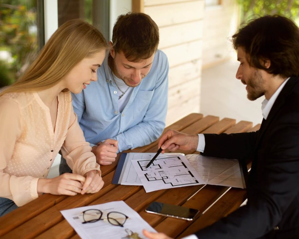 property-manager-showing-house-plan-to-his-clients-at-table-on-porch.jpg